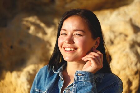 portrait of a woman in a denim jacket on a background of yellow rock.の写真素材
