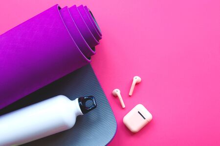 purple yoga mat, water bottle and headphones on a pink background.の写真素材