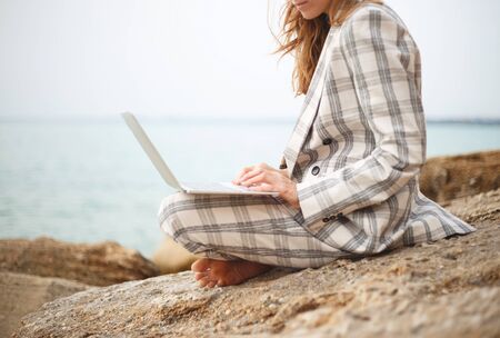 girl with a laptop by the sea. remote work concept.の写真素材
