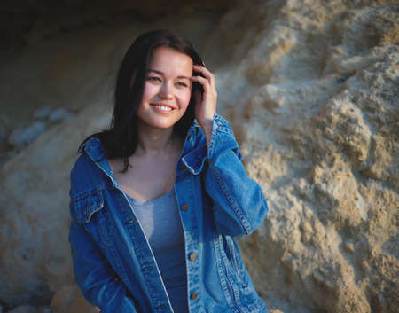 portrait of a woman in a denim jacket on a background of yellow rock.の写真素材