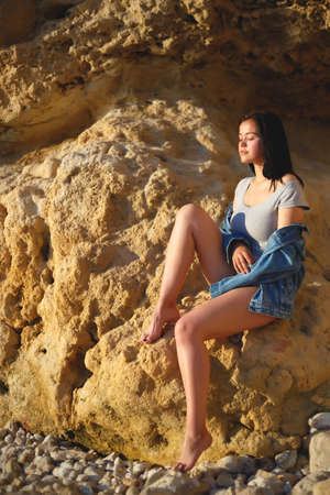 portrait of a woman in a denim jacket on a background of yellow rock.の写真素材