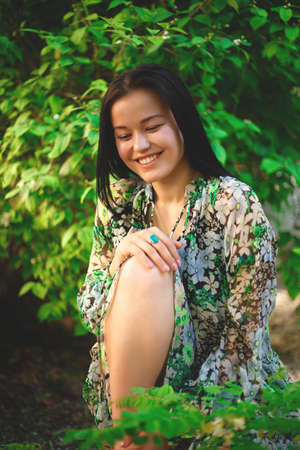 portrait of a beautiful smiling brunette on a background of greenery.の写真素材