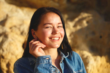 portrait of a woman in a denim jacket on a background of yellow rock.の写真素材
