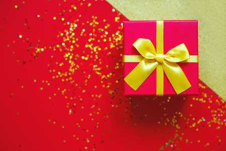 gift box with bow on red-gold background.の写真素材