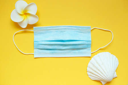 medical mask with a flower and a shell on a yellow background.の写真素材