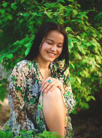 portrait of a beautiful smiling brunette on a background of greenery.の写真素材