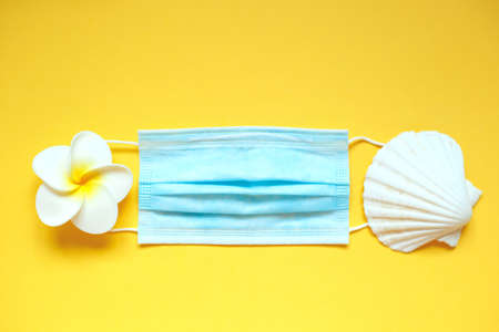 medical mask with a flower and a shell on a yellow background.の写真素材
