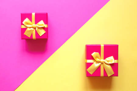 two gift boxes with bow on yellow and pink background.の写真素材