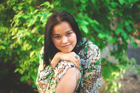 portrait of a beautiful smiling brunette on a background of greenery.の写真素材