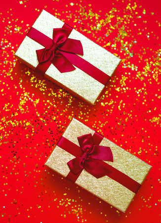 two gift box with bowes on red-gold background.の写真素材
