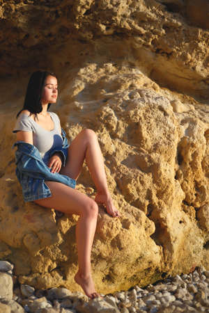 portrait of a woman in a denim jacket on a background of yellow rock.の写真素材
