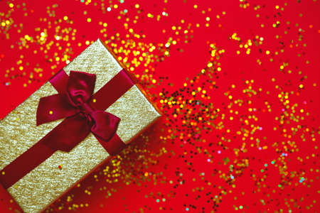 gift box with bow on red-gold background.の写真素材
