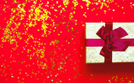 gift box with bow on red-gold background.の写真素材