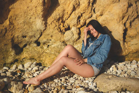 portrait of a woman in a denim jacket on a background of yellow rock.の写真素材