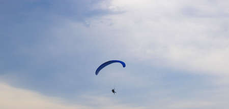 a man on a paraglider on the background of a cloudy blue sky.の写真素材