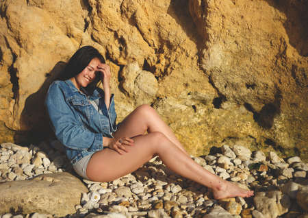 portrait of a woman in a denim jacket on a background of yellow rock.の写真素材