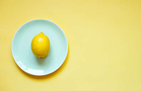 ripe lemon on a green plate on a yellow background.の写真素材