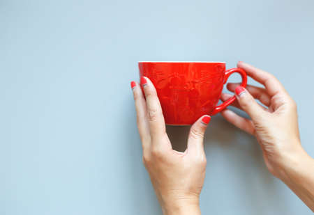 female hands with beautiful manicure hold a red christmas cup.の写真素材