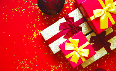 gift boxes with bows and Christmas toys on a red-gold background.の写真素材