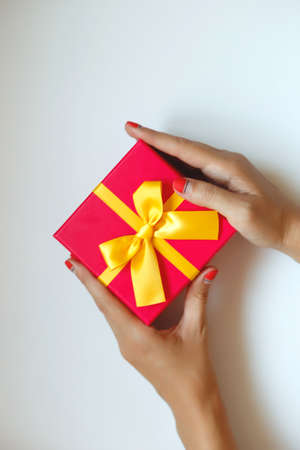 female hands with beautiful manicure hold a gift boxの写真素材