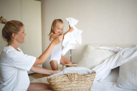 mom and daughter disassemble a wicker basket of laundryの写真素材