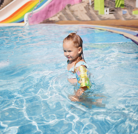 little girl swims in the pool in the outdoor water park.の写真素材