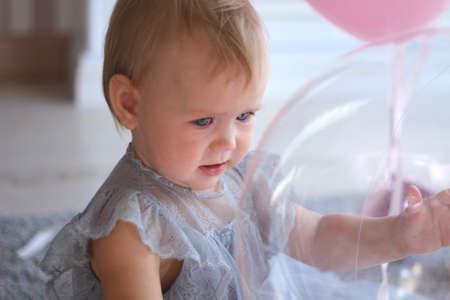 little girl in a beautiful dress pulls her hand to the balloonsの写真素材