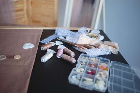 a stack of fabrics and sewing accessories on a tailor's table.
