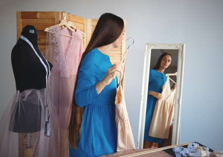 young beautiful seamstress trying on a new product in front of the mirror.の写真素材
