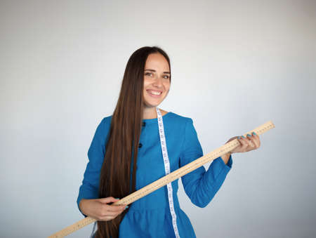 portrait of a young beautiful seamstress in blue dress.