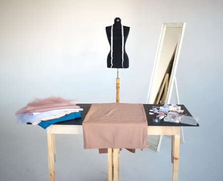 a stack of fabrics and sewing accessories on a tailor's table.の写真素材