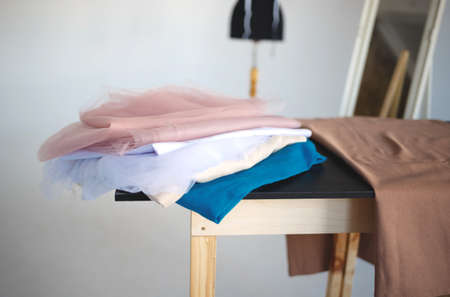 a stack of fabrics and sewing accessories on a tailor's table.の写真素材