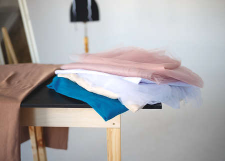 a stack of fabrics and sewing accessories on a tailor's table.の写真素材