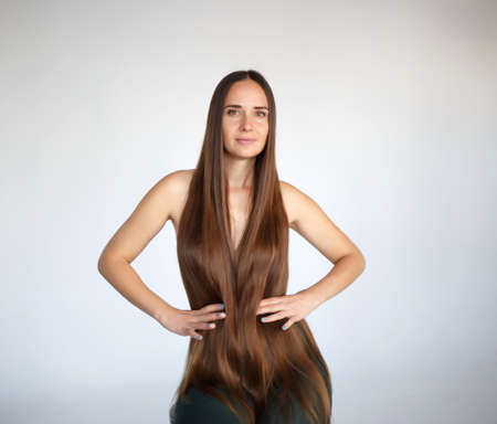 young beautiful woman with very long hair sits on a chair.の写真素材