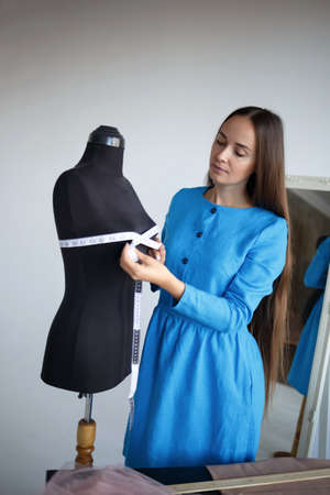 young beautiful seamstress and manikin at her workplace.の写真素材