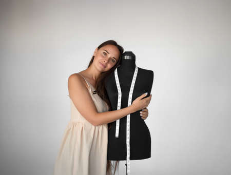 young beautiful seamstress hugs a manikin at her workplace.の写真素材