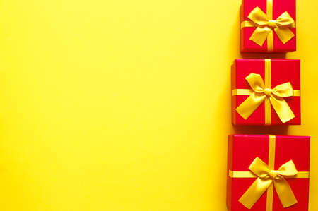 three bright red gift boxes on yellow backgroundの写真素材