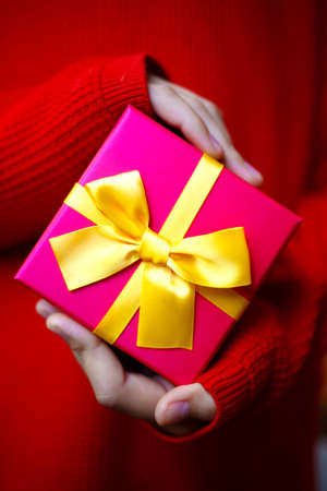 beautiful bright gift in the hands of a child on a red background.の写真素材
