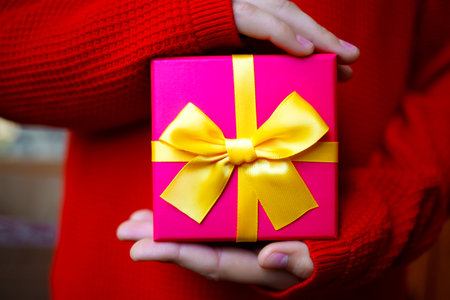 beautiful bright gift in the hands of a child on a red background.の写真素材