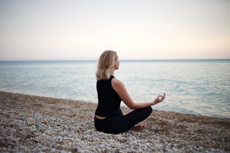 young beautiful woman meditates by the sea.の写真素材