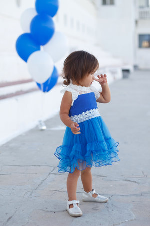 little girl in a beautiful dress with a huge fountain of balloonsの写真素材