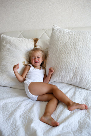 little girl crying lying on the bedの写真素材