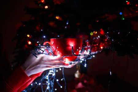red cup in hands wrapped in a Christmas garlandの写真素材