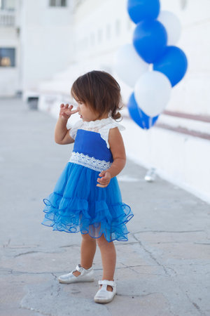little girl in a beautiful dress with a huge fountain of balloons.の写真素材