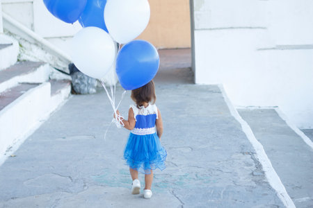 little girl in a beautiful dress with a huge fountain of balloons.の写真素材