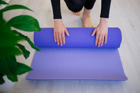 young woman unfolds yoga mat before practice.の写真素材