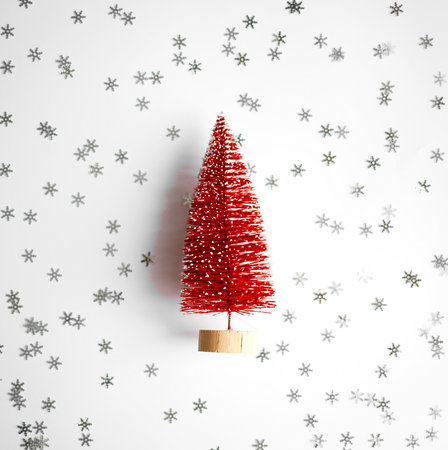 small red christmas tree on a white background with silvery snowflakes.の写真素材