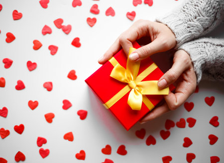 hands hold a gift on a white background with red hearts.の写真素材