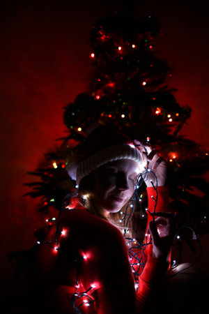 portrait of a young woman in a hat of Santa Claus in a garland.の写真素材