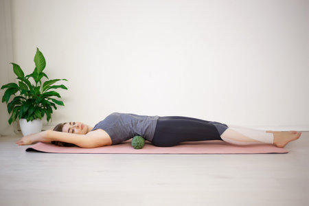 young beautiful woman lies on a massage roller for the back on a sports mat.の写真素材